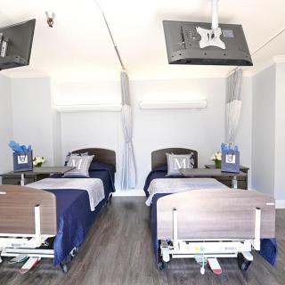 A modern hospital room with two neatly arranged beds and medical equipment.