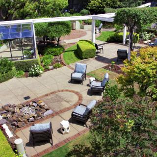 A beautifully landscaped garden with a patio, outdoor seating, and a fire pit area.