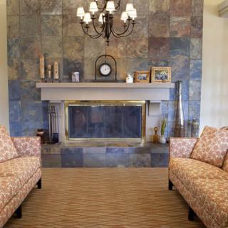 A cozy living room featuring a stylish fireplace with decorative items on the mantel and patterned sofas facing each other.