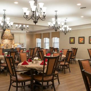 An elegantly decorated dining room with wooden tables and chairs, illuminated by chandeliers.