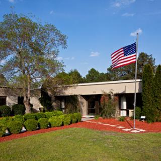 A well-maintained building with an American flag flying proudly in front, surrounded by neat landscaping.