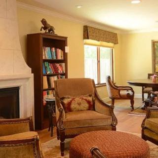 Cozy living room with armchairs, a bookshelf, and a fireplace.