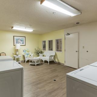 A well-lit laundry room with washing machines and a cozy seating area.
