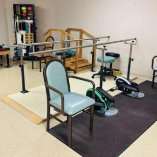 A physical therapy room equipped with exercise machinery and parallel bars for rehabilitation exercises.