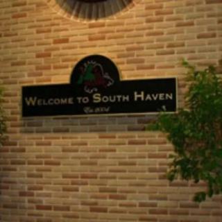 A welcome sign for South Haven displayed on a brick wall indoors.
