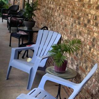 A cozy patio area with blue chairs and potted plants against a brick wall.