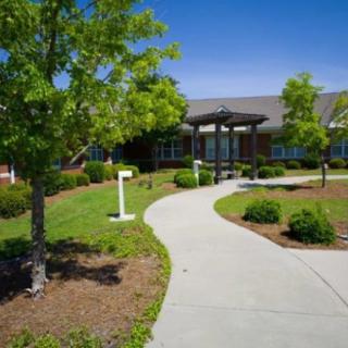 A well-landscaped building entrance with a curving pathway on a sunny day.