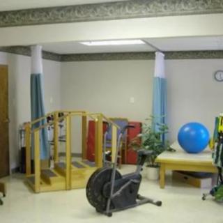 A rehabilitation room featuring various therapy and exercise equipment, including a stationary bike and exercise ball.