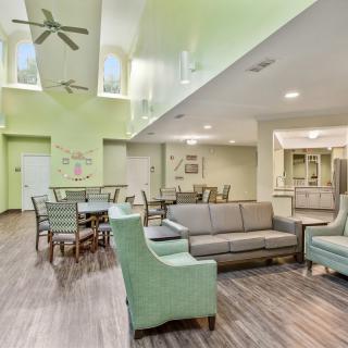A modern living room with green walls, featuring comfortable seating and dining areas.