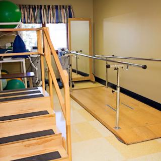 A physical therapy room equipped with parallel bars and stairs for rehabilitation exercises.