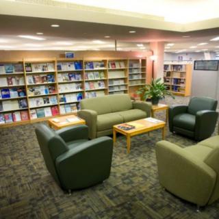 A cozy library seating area with sofas and bookshelves filled with books.