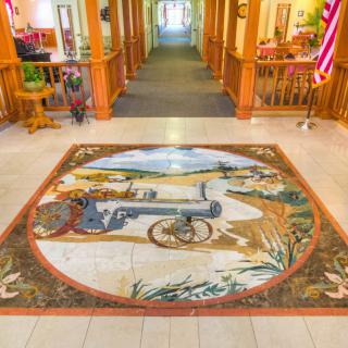 A vibrant mural depicting historical scenes adorning the floor of a brightly lit hallway.