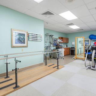 A spacious physical therapy room equipped with rehabilitation tools and a mirrored area for patient assessment.