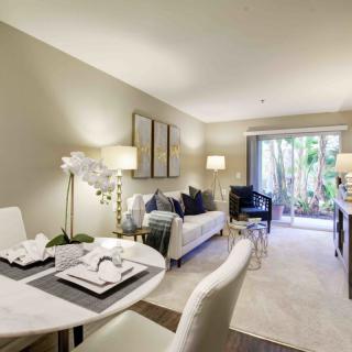 A modern living room with a dining area, featuring elegant furniture and abundant natural light.
