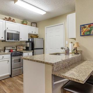 A modern kitchen with white cabinets, granite countertops, and stainless steel appliances.