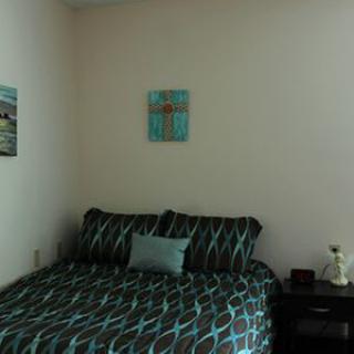 A cozy bedroom with a patterned bedspread and a nightstand.