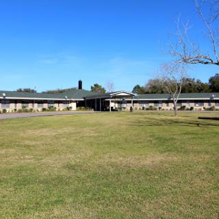 A serene view of a modern building set against a vibrant blue sky and lush green grass.
