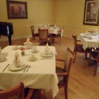 An elegant dining room with neatly set tables and a piano in the corner.