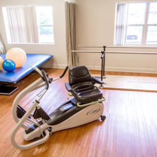 A modern rowing machine set up in a bright, spacious fitness area designed for rehabilitation and physical therapy.