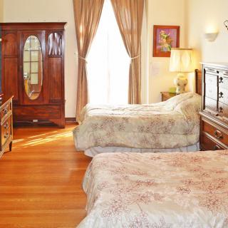 A cozy bedroom with vintage furniture, featuring two beds and an armoire.
