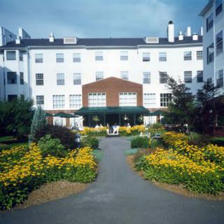 A building with a beautifully landscaped garden and pathway lined with vibrant flowers.