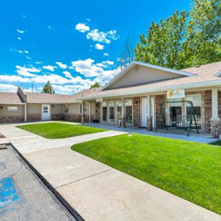 A well-maintained residential building with a green courtyard under a bright blue sky.