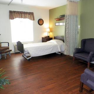A well-furnished patient room with a bed, seating area, and natural light.