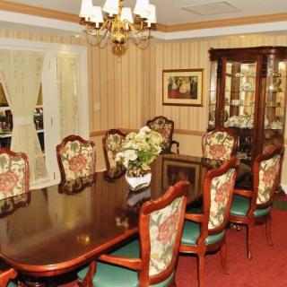 Elegant dining room with a classic design featuring a large wooden table, ornate chairs, and a chandelier.
