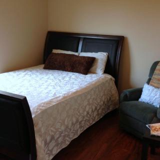 A cozy bedroom with a bed and a chair.
