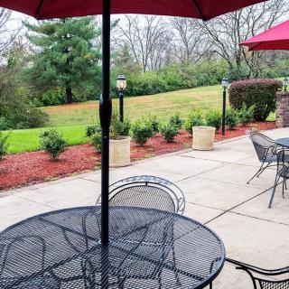 A peaceful outdoor patio with tables and umbrellas overlooking a garden.