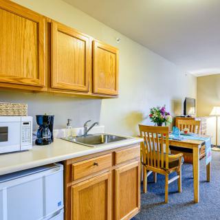 Compact kitchenette in a hotel room with wooden cabinets and a small dining area.