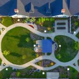 Aerial view of a landscaped garden with winding pathways and adjacent buildings.