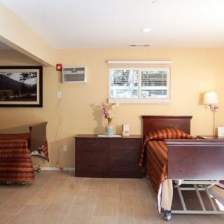 A cozy bedroom with simple decor, featuring a bed, dresser, lamp, and artwork on the walls.