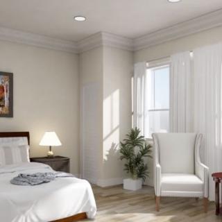 A cozy bedroom with a bed, lamp, and chair by a window.
