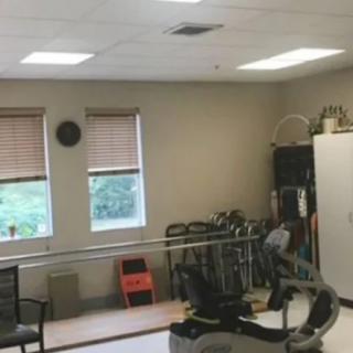A rehabilitation room featuring parallel bars and exercise equipment.