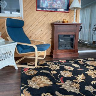 A cozy living room setup featuring a comfortable chair beside a decorative fireplace, complemented by an elegant rug.