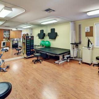 A well-equipped physical therapy room with treatment tables and various exercise equipment.