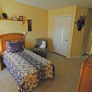 A cozy bedroom with a single bed, armchair, and decorative elements on the wall.