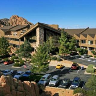 A scenic view of a resort nestled among rocky mountains, featuring a parking lot and lush greenery.