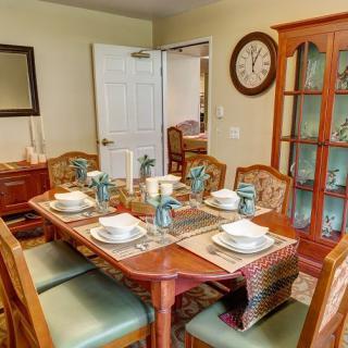 A cozy dining room with a set table for six, featuring elegant tableware and decor.
