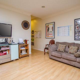 A cozy living room with a sofa, television, and framed artwork on the walls.