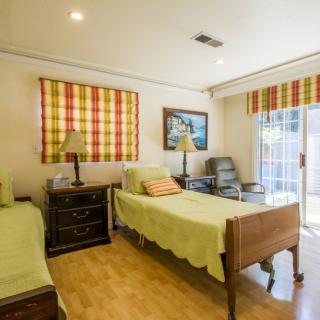 A cozy bedroom with two beds, colorful curtains, and wooden flooring.