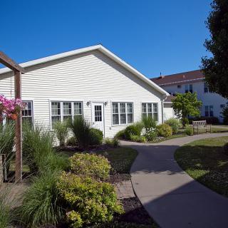 A cozy residential house with a well-maintained garden and pathway on a sunny day.