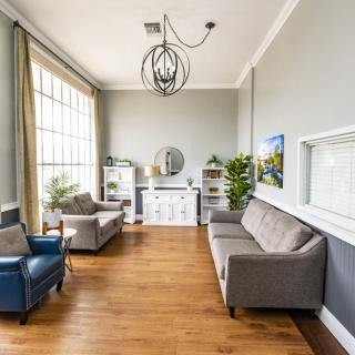 A modern living room with stylish furniture, large windows, and a chandelier.