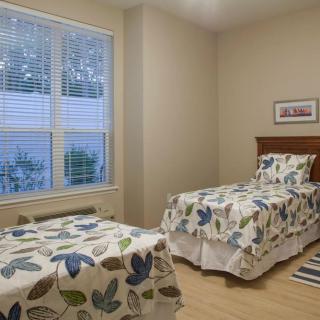A cozy bedroom with twin beds featuring floral bedding and a large window.