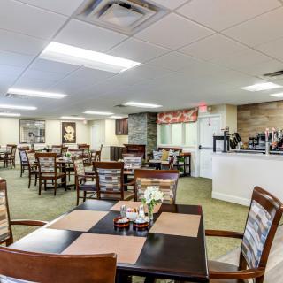 An inviting dining area with multiple tables and chairs neatly arranged, featuring warm decor and bright lighting.