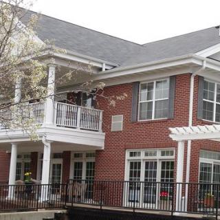 A two-story brick house with a balcony and multiple windows.