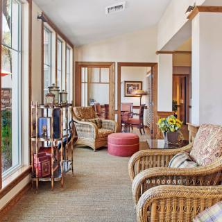 A cozy living room interior featuring natural light from large windows, wicker furniture, and decorative elements.