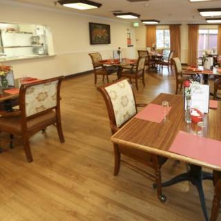 A cozy restaurant dining area with wooden flooring and neatly arranged tables and chairs.