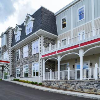 A modern residential building with a stone facade and multiple balconies.